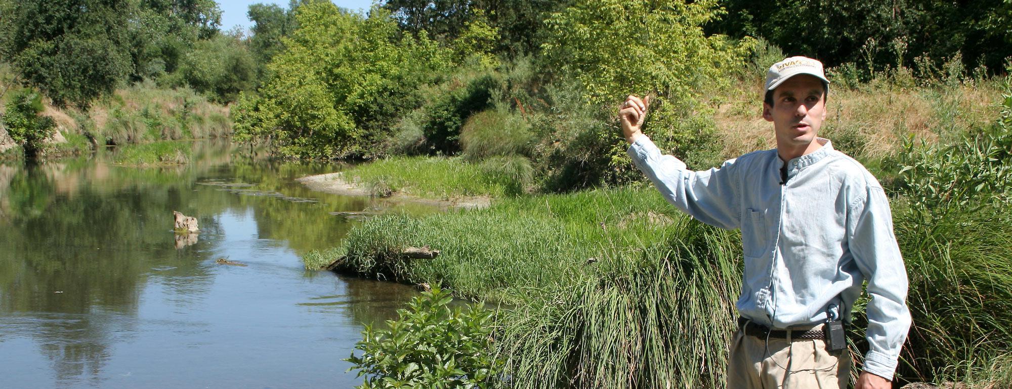 A amjs澳金沙门 researcher points at a wetlands areas behind him
