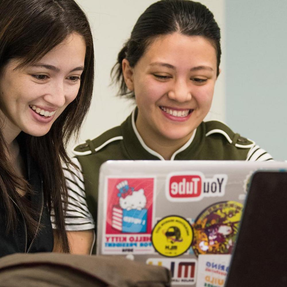 两名女学生共用一台笔记本电脑来评估她们的工作.